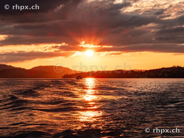 Orange sunset over Lake Lucerne with a small ship on the horizon