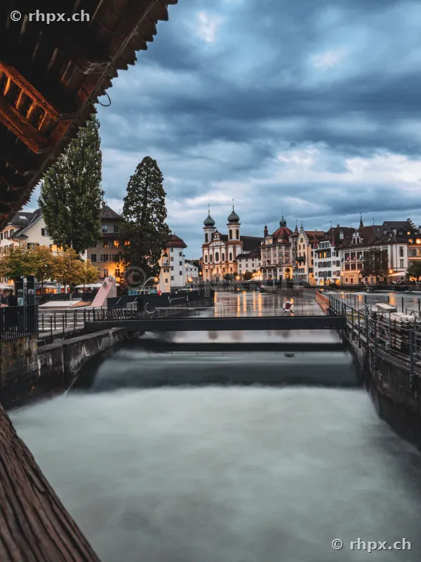 View from Chapel Bridge across the Reuss weir towards the Jesuit Church in Lucerne at dusk