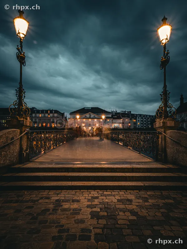 View across the Theater Bridge towards the Lucerne Theater under a cloudy evening sky