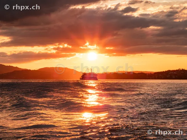 A ship sailing on Lake Lucerne during an orange sunset
