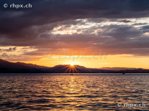 The sun sets behind the hills over Lake Lucerne