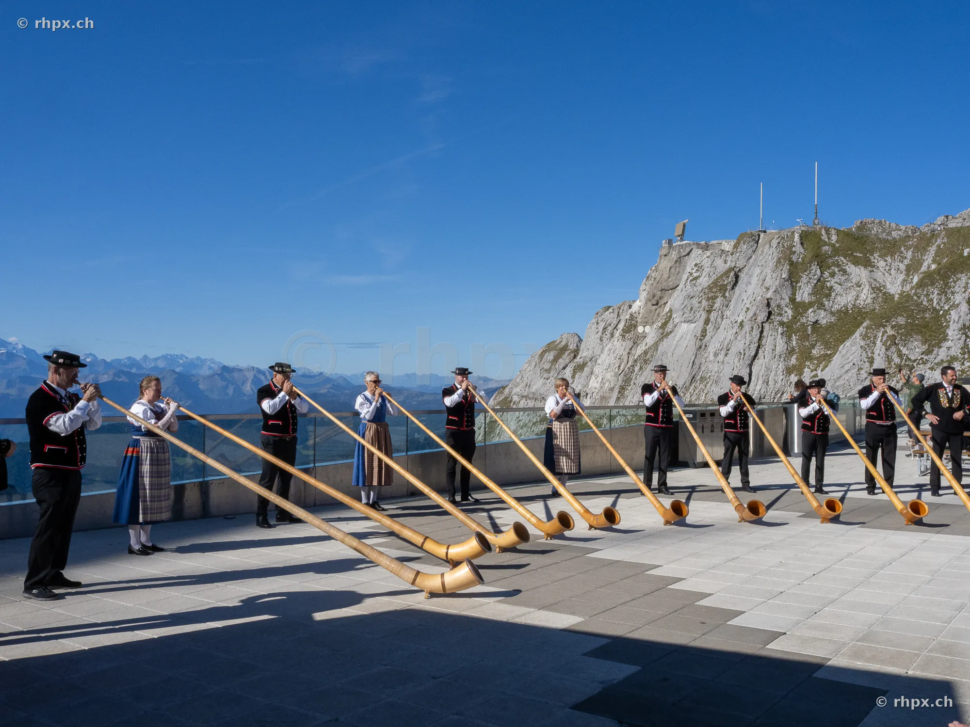 Group of alphorn players in traditional Swiss costume on a terrace at Mount Pilatus