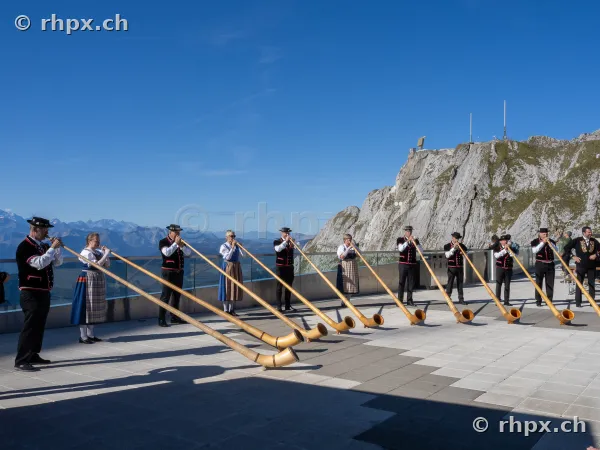 Group of alphorn players in traditional Swiss costume on a terrace at Mount Pilatus