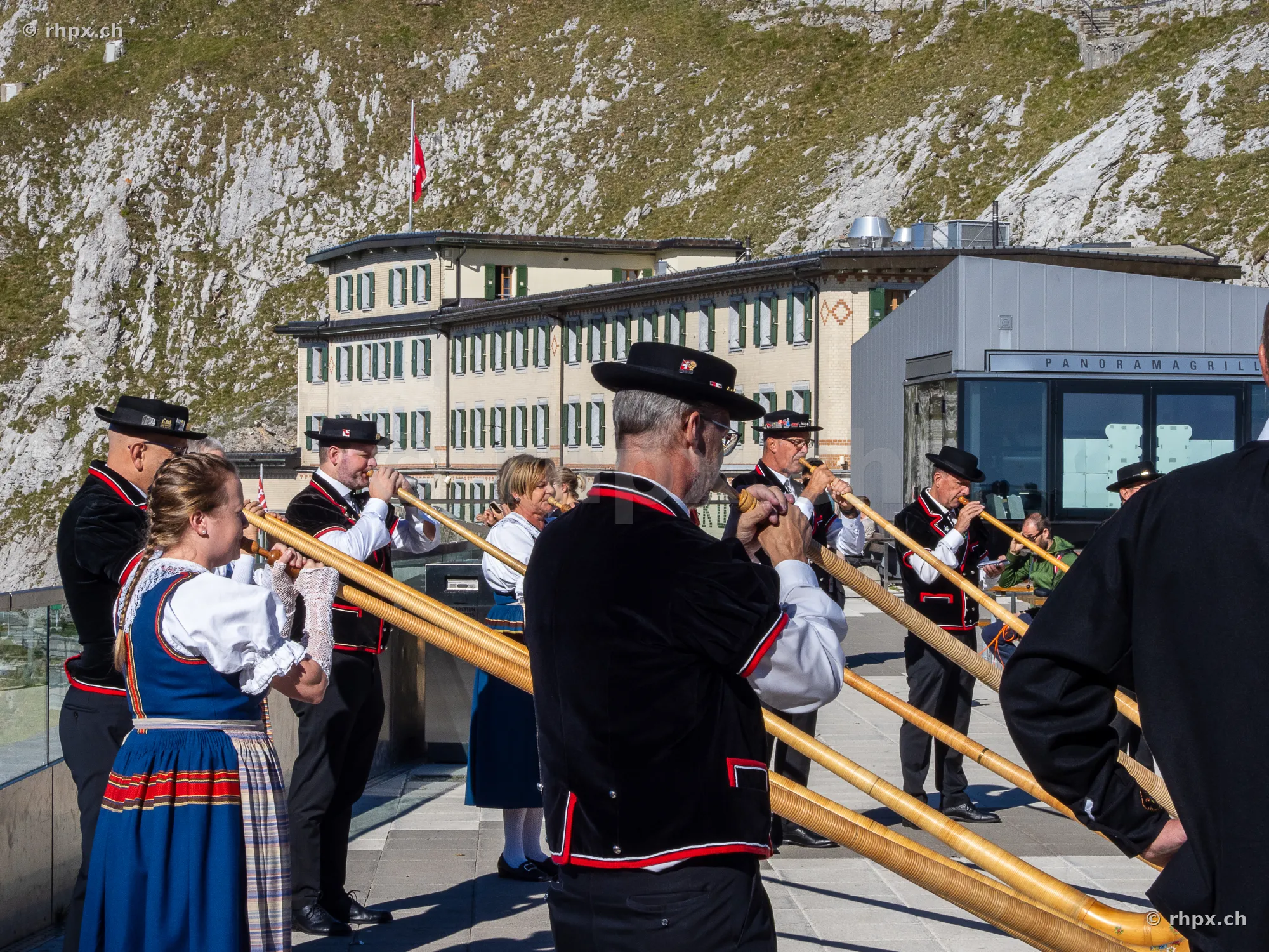 Alphornbläser in traditioneller Tracht beim Hotel Pilatus-Kulm vor der Felswand
