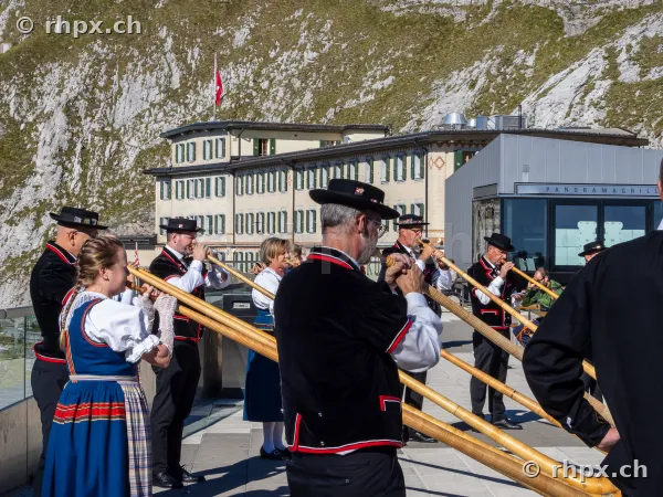 Alphornbläser in traditioneller Tracht beim Hotel Pilatus-Kulm vor der Felswand