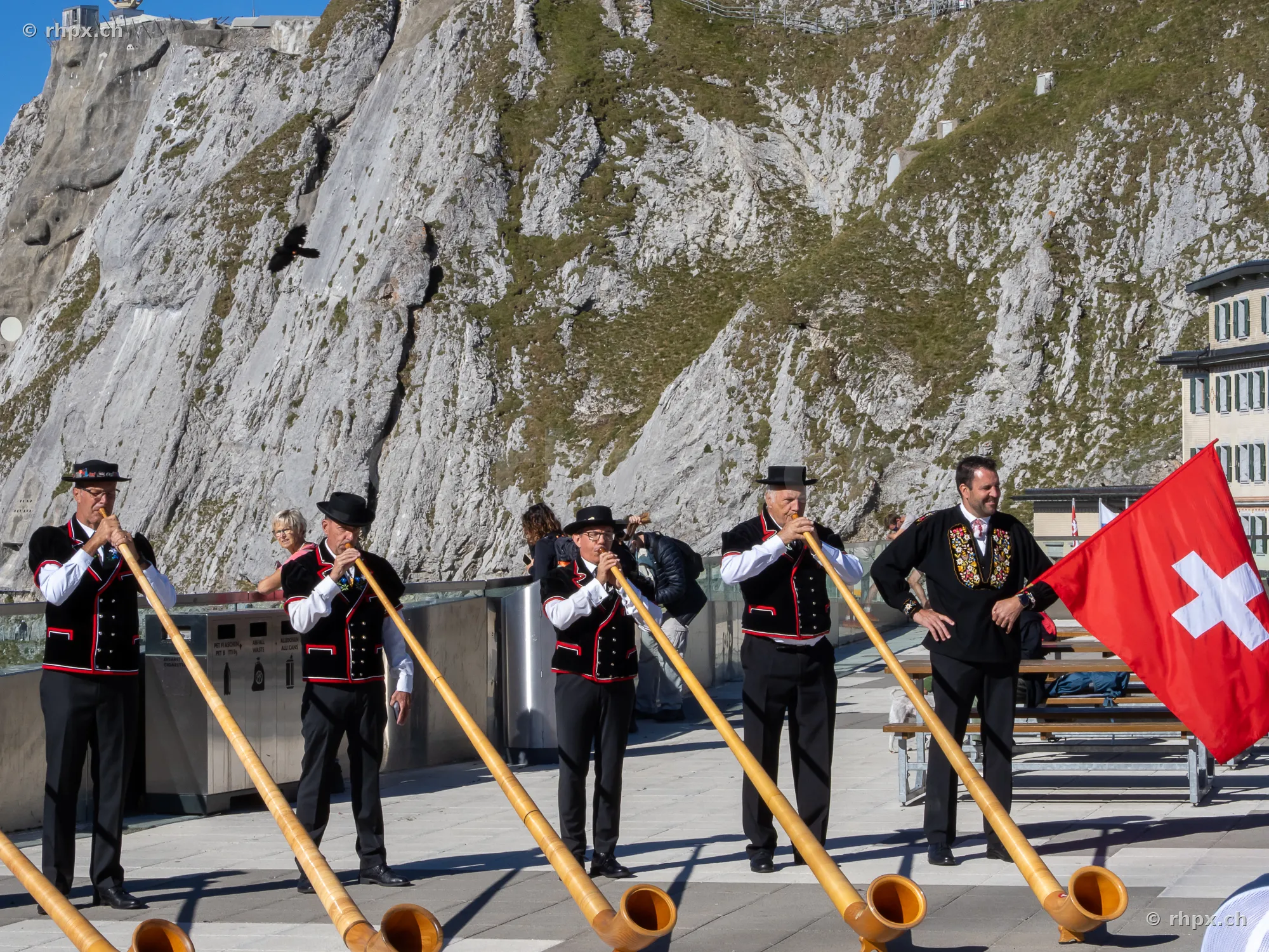 Group of alphorn players in traditional Swiss costume in front of the Pilatus rock face
