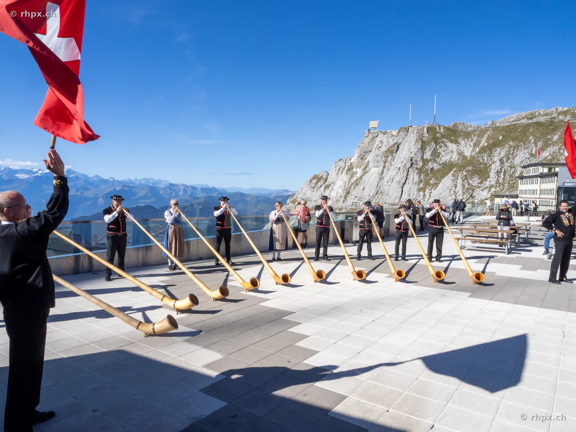 Group of alphorn players in front of the Hotel Bellevue on Mount Pilatus in clear weather