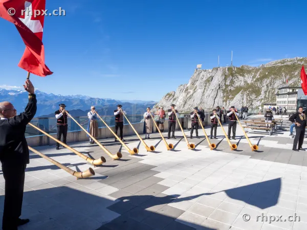 Group of alphorn players in front of the Hotel Bellevue on Mount Pilatus in clear weather