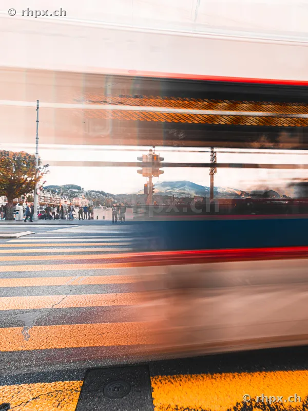 Motion blur of a passing tram in front of the Lake Lucerne waterfront with a pedestrian crossing