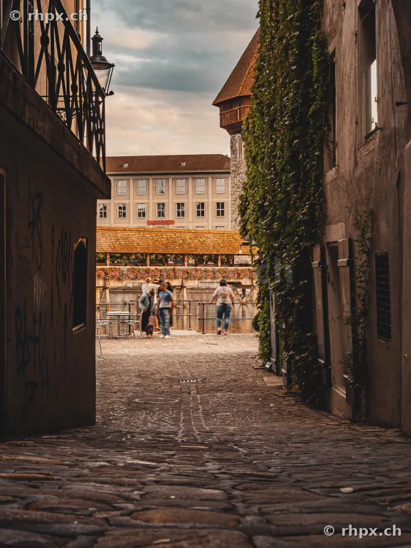 Kopfsteinpflastergasse in der Luzerner Altstadt mit Blick auf die Kapellbrücke und den Wasserturm