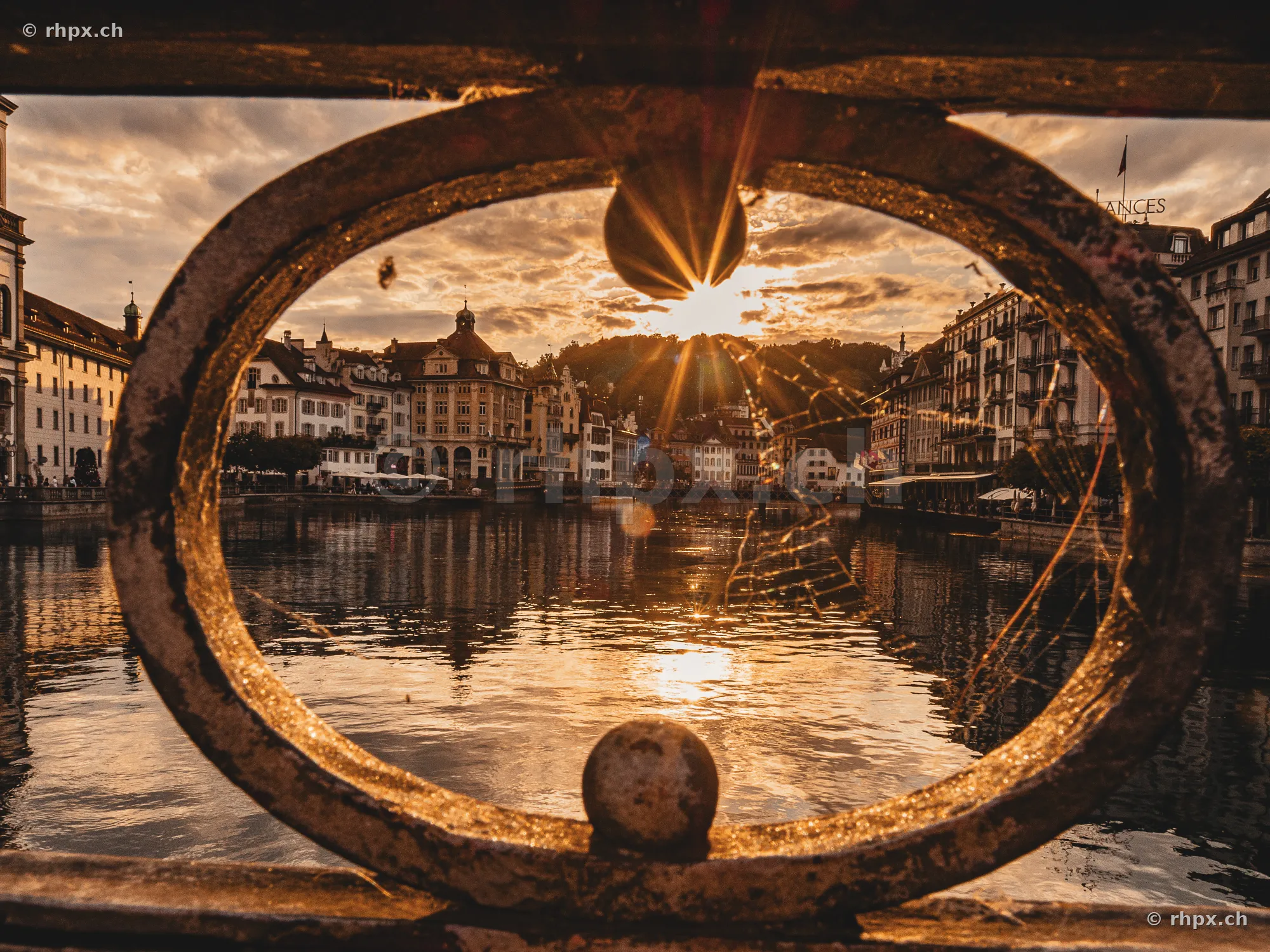 Blick durch ein rundes Geländer auf die von der Abendsonne beleuchtete Reuss in Luzern