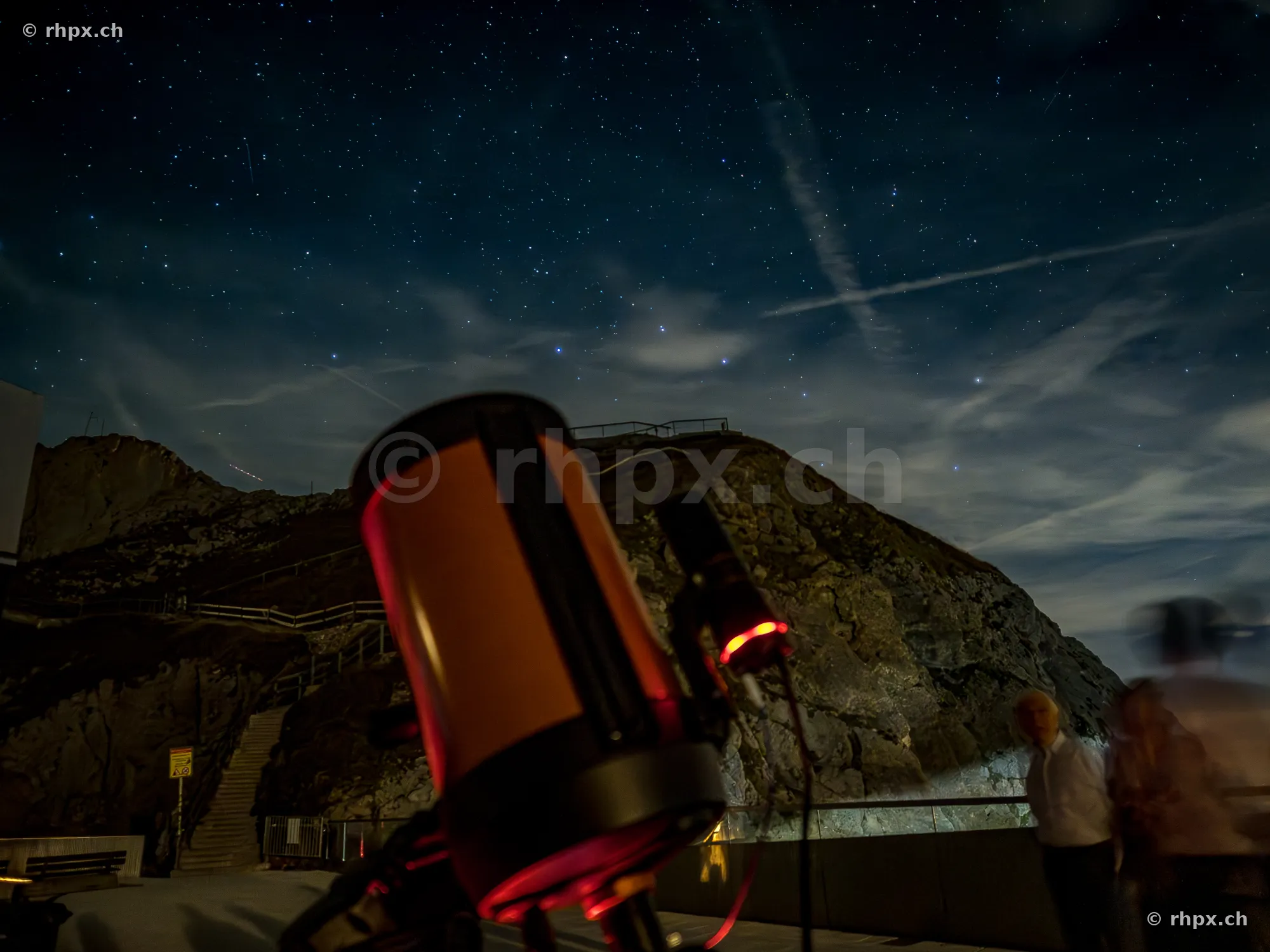 View of a telescope in front of Mount Pilatus at night with a starry sky