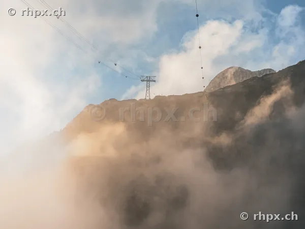 Stütze der Luftseilbahn am felsigen Berghang des Pilatus, umgeben von Wolken und Nebel.