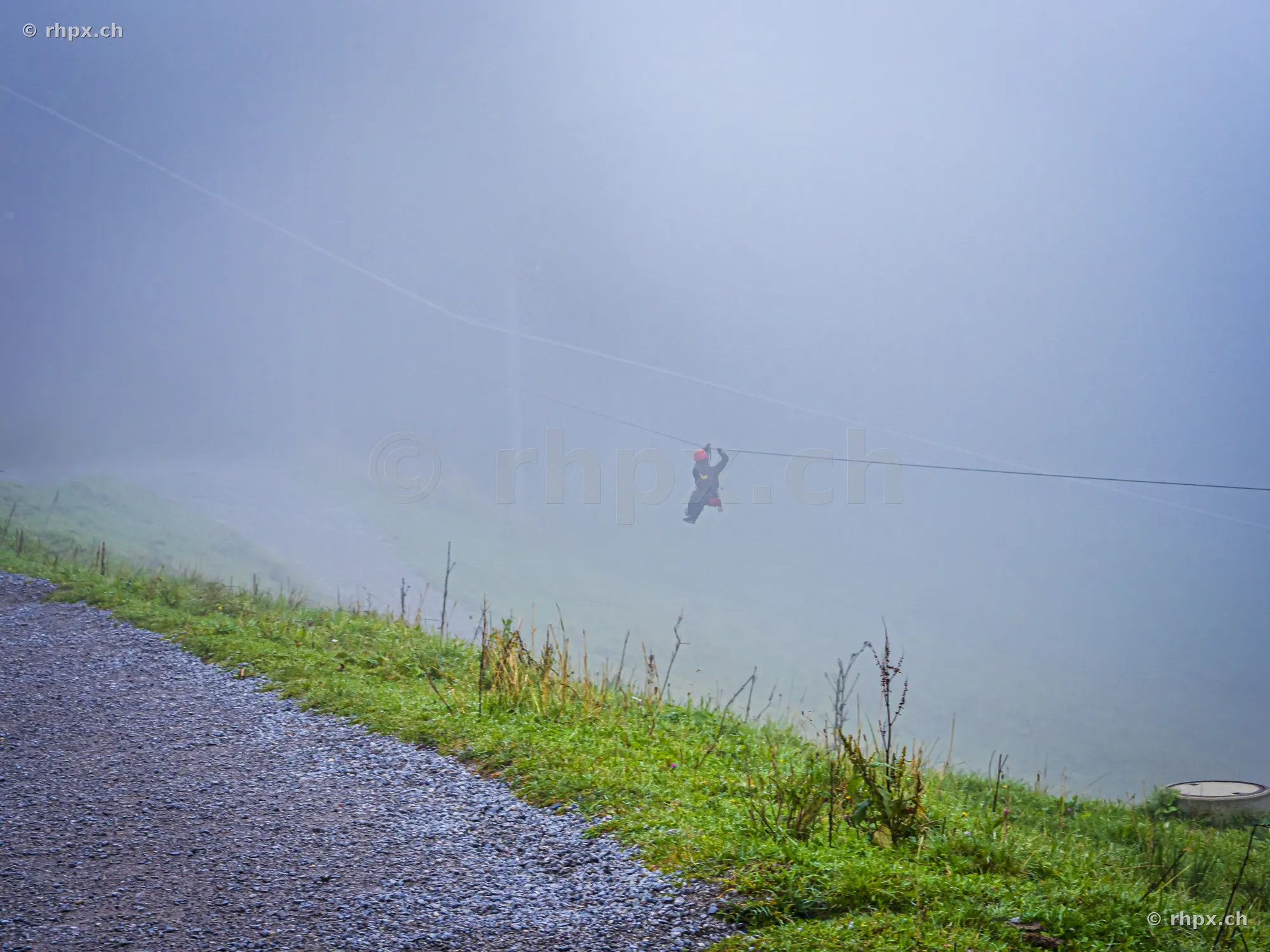 A person riding a zip line in dense fog at Mount Pilatus