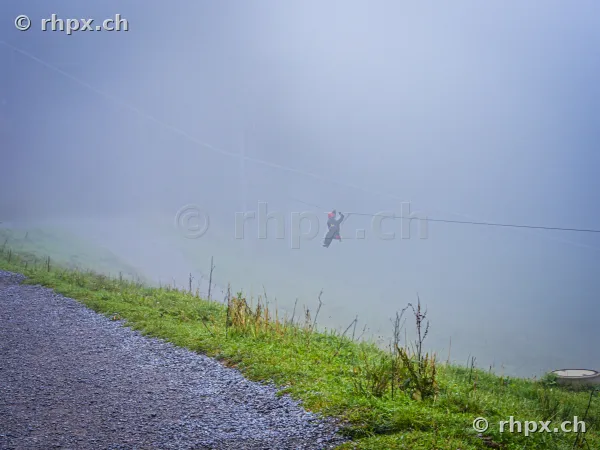 A person riding a zip line in dense fog at Mount Pilatus
