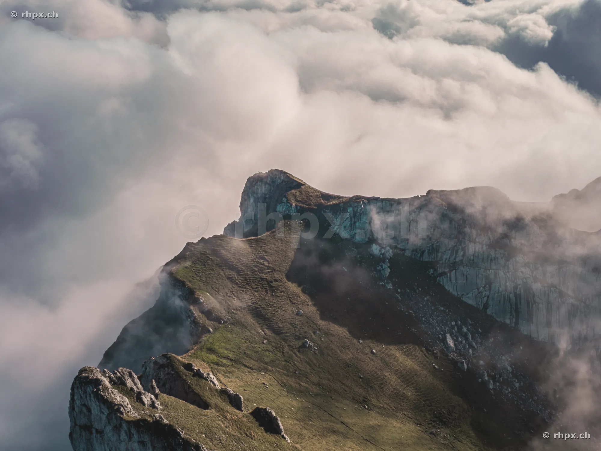 Blick auf den felsigen Bergkamm des Pilatus, der aus einer dichten Wolkendecke hervorragt.