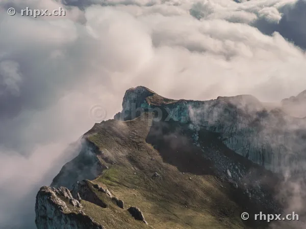Blick auf den felsigen Bergkamm des Pilatus, der aus einer dichten Wolkendecke hervorragt.