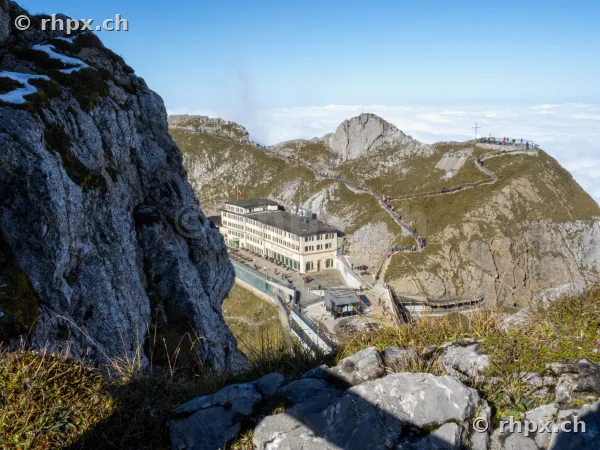View from the rocks over the Hotel Bellevue and the summit path of Mount Pilatus above a sea of clouds