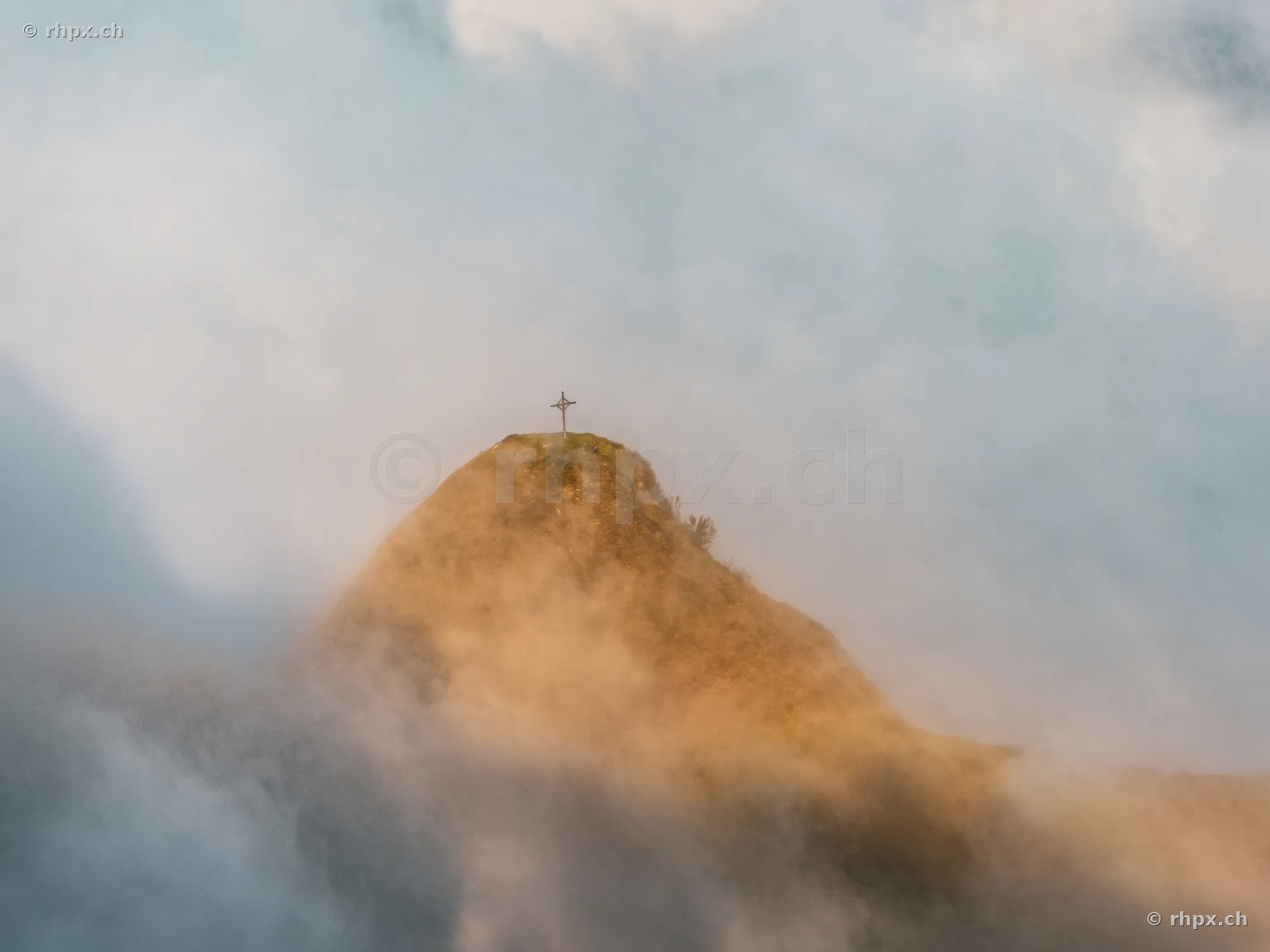 Das Gipfelkreuz auf dem Pilatus umgeben von ziehenden Nebelschwaden