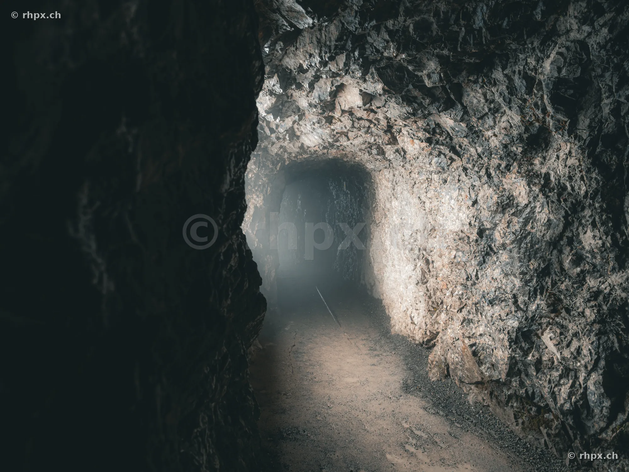 View through a rock tunnel of the Dragon Cave at Pilatus with misty exit