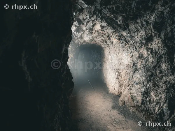 View through a rock tunnel of the Dragon Cave at Pilatus with misty exit