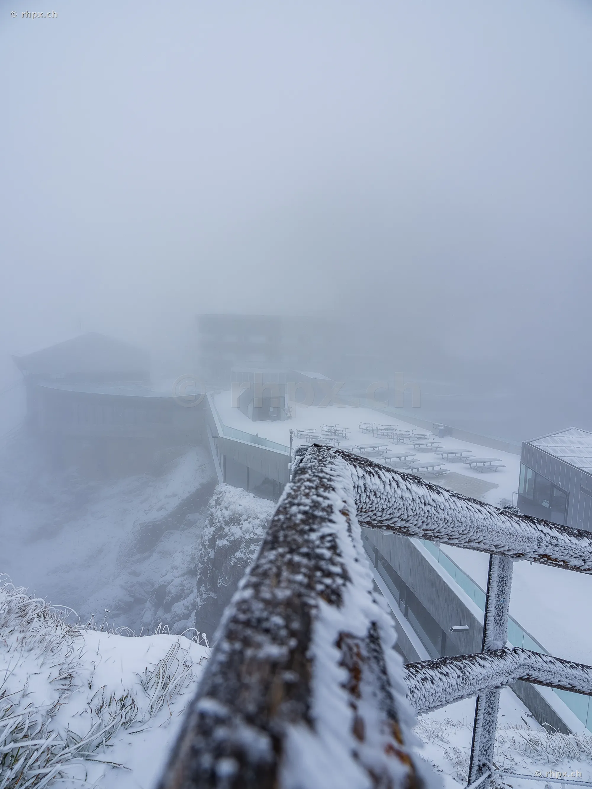Snow-covered railing and view of the foggy hotel terrace on Mount Pilatus