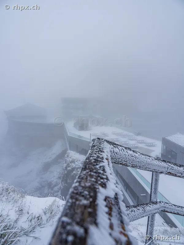 Snow-covered railing and view of the foggy hotel terrace on Mount Pilatus