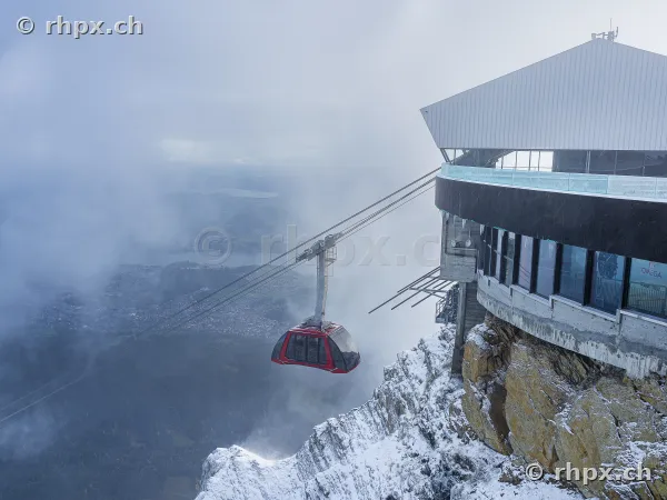 Rote Luftseilbahn vor dem verschneiten Pilatus Gipfel in der Nebeldecke