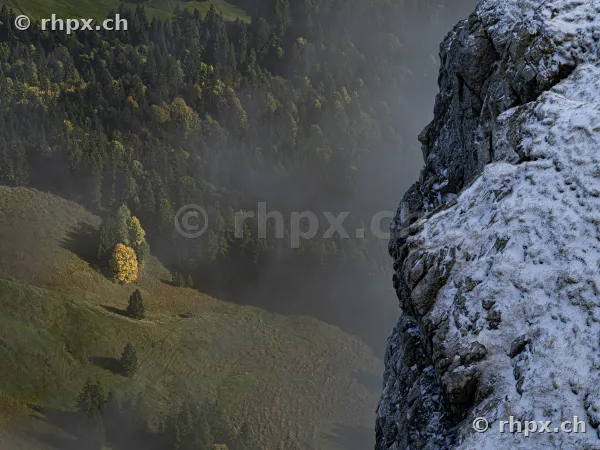 Steep snow-covered rock face on Mount Pilatus overlooking misty forests