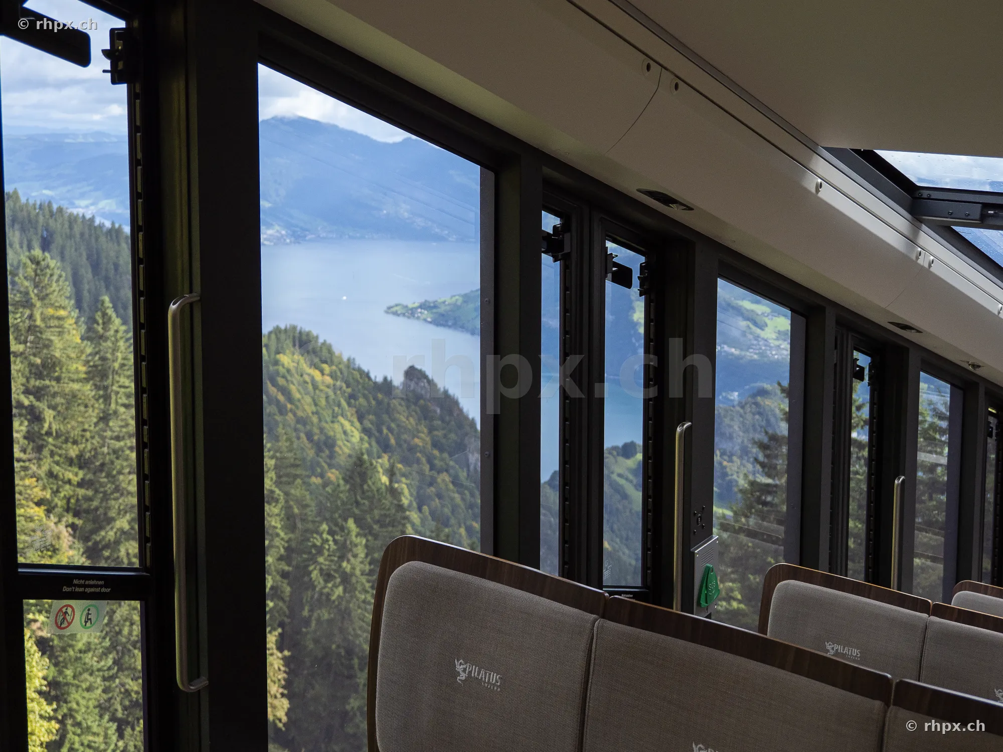 View from a Pilatus railway train window towards Lake Lucerne and forested hills