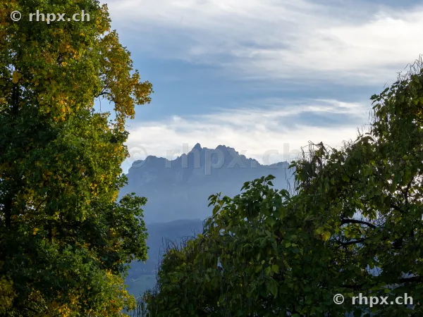 View of the Pilatus mountain range framed by autumn-colored trees.