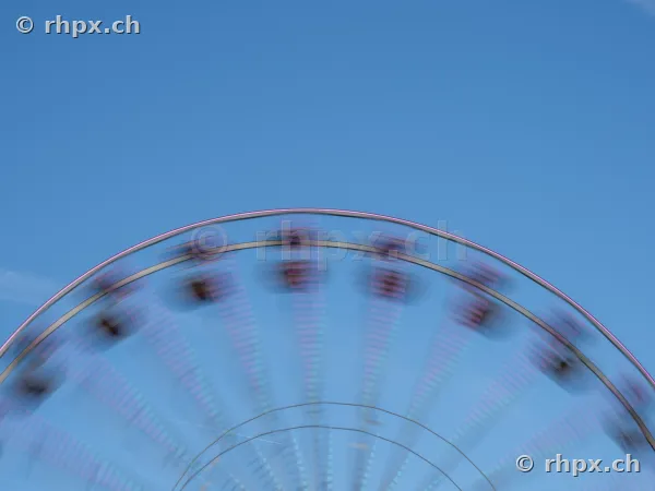 Der obere Teil eines sich drehenden Riesenrades vor wolkenlosem blauem Himmel