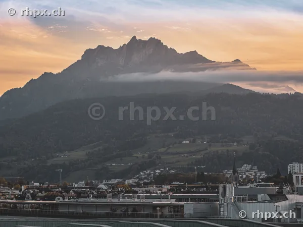 Der Berg Pilatus bei Luzern unter einem orangefarbenen Abendhimmel mit Wolkenbändern