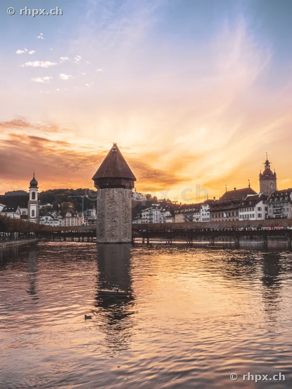 The Chapel Bridge with the water tower in Lucerne during sunset on the Reuss river.