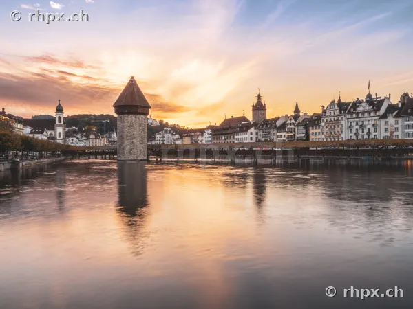 Chapel Bridge and water tower in Lucerne with the old town silhouette at sunset
