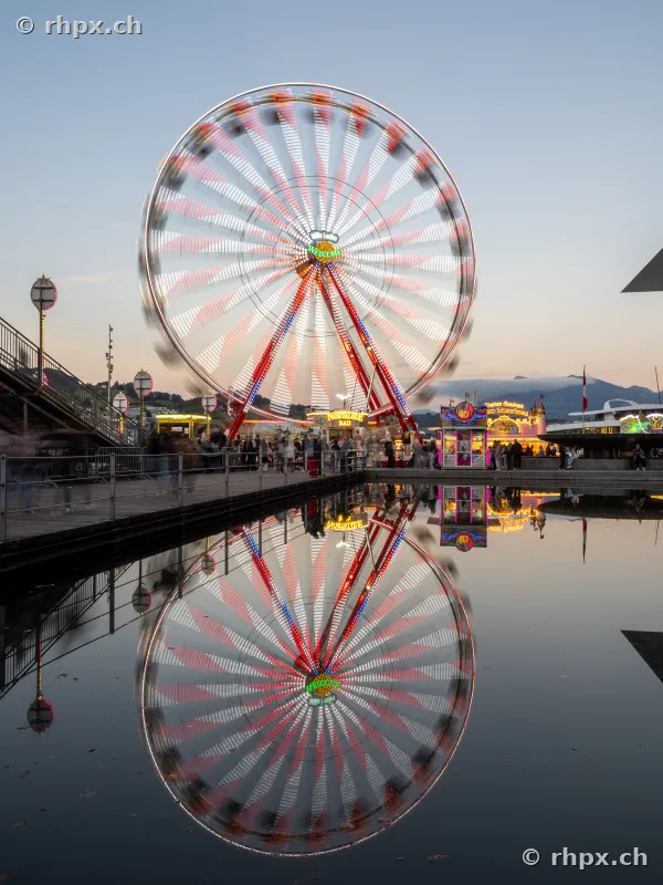 Ferris wheel at the Lucerne autumn fair reflected in the water