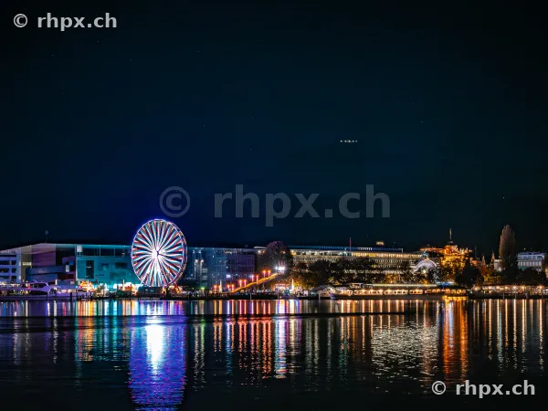Nächtlicher Blick auf das beleuchtete Riesenrad und das KKL am Vierwaldstättersee in Luzern