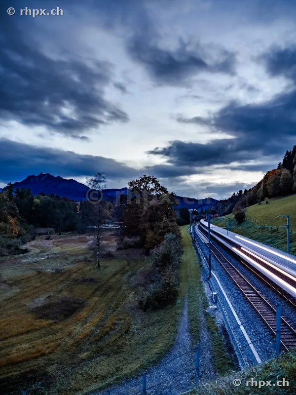Passing train with motion blur in front of Mount Pilatus at dusk