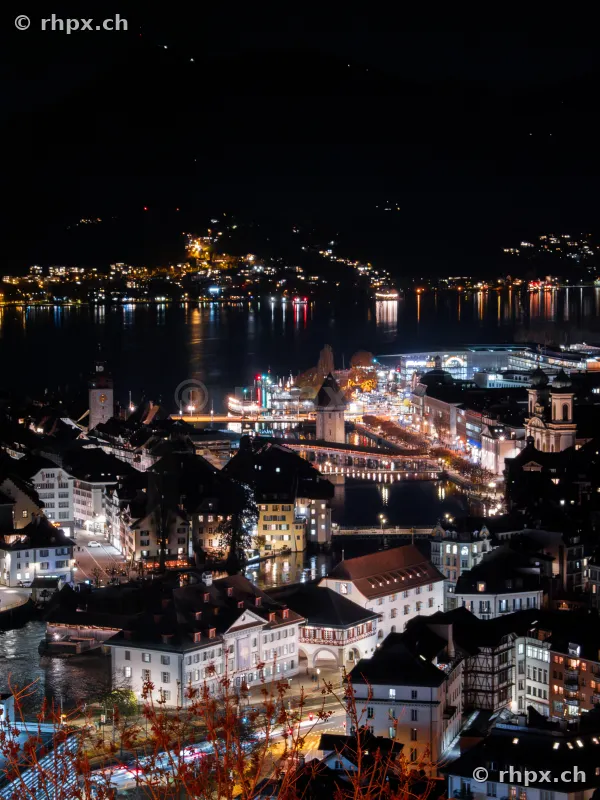 Blick von oben auf die beleuchtete Luzerner Altstadt mit Kapellbrücke bei Nacht