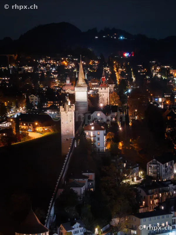 Blick auf die beleuchtete Museggmauer und ihre Wehrtürme in der Stadt Luzern bei Nacht