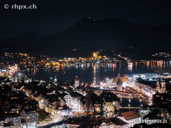 Luftaufnahme von Luzern bei Nacht mit beleuchteter Kapellbrücke und Vierwaldstättersee