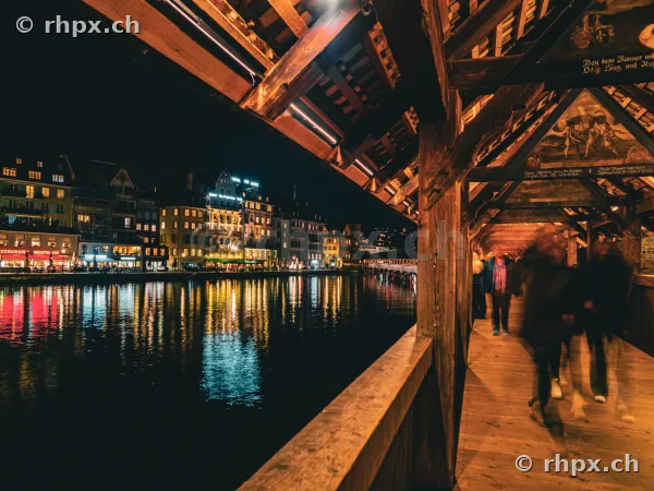Blick aus der Kapellbrücke über die nächtliche Reuss mit den beleuchteten Häusern der Altstadt von Luzern