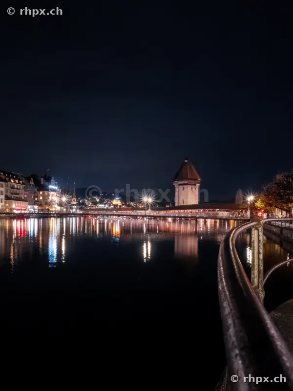Night view of the illuminated Chapel Bridge in Lucerne with water tower.