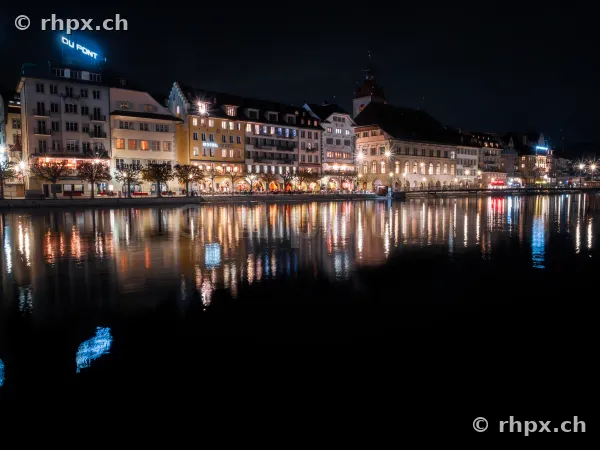 Die nächtliche Häuserzeile entlang der Reuss in Luzern mit Spiegelungen im Wasser