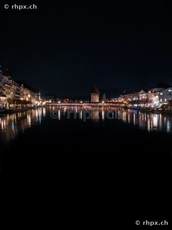 Night view of the illuminated Chapel Bridge with water tower in Lucerne.