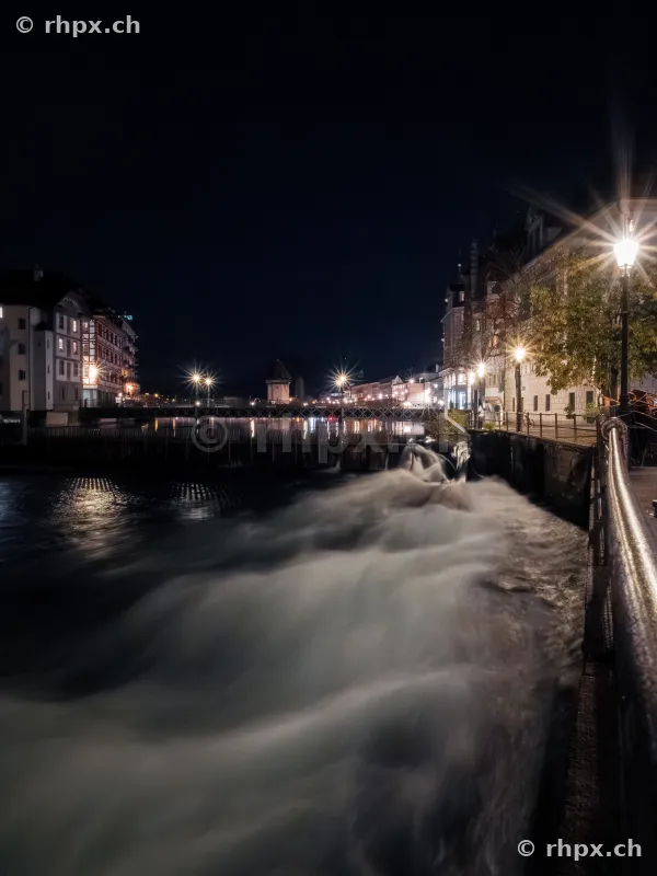 Night view of the Reuss weir in Lucerne with light reflections