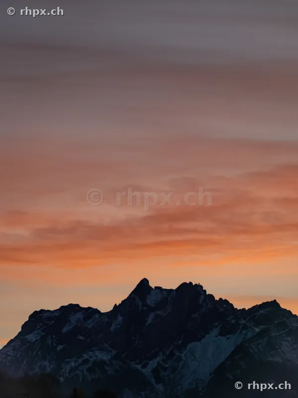 Silhouette des Berges Pilatus vor einem orange gefärbten Abendhimmel