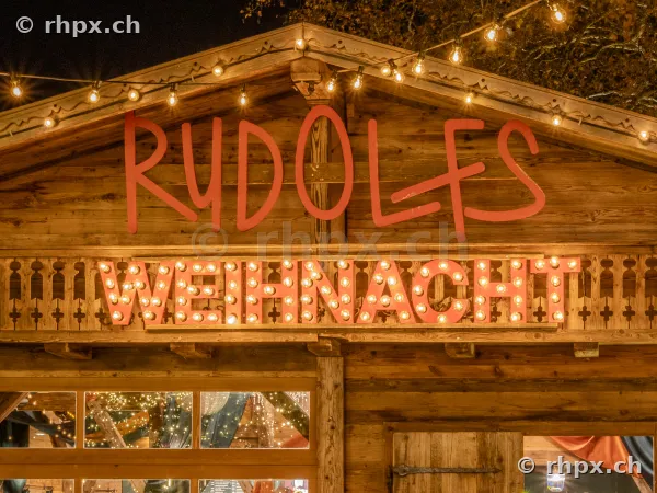 Illuminated wooden facade of a Christmas market stall named Rudolfs in Lucerne
