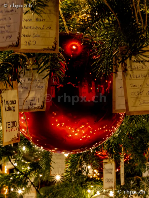 Red Christmas bauble with wish cards on an illuminated tree in Lucerne
