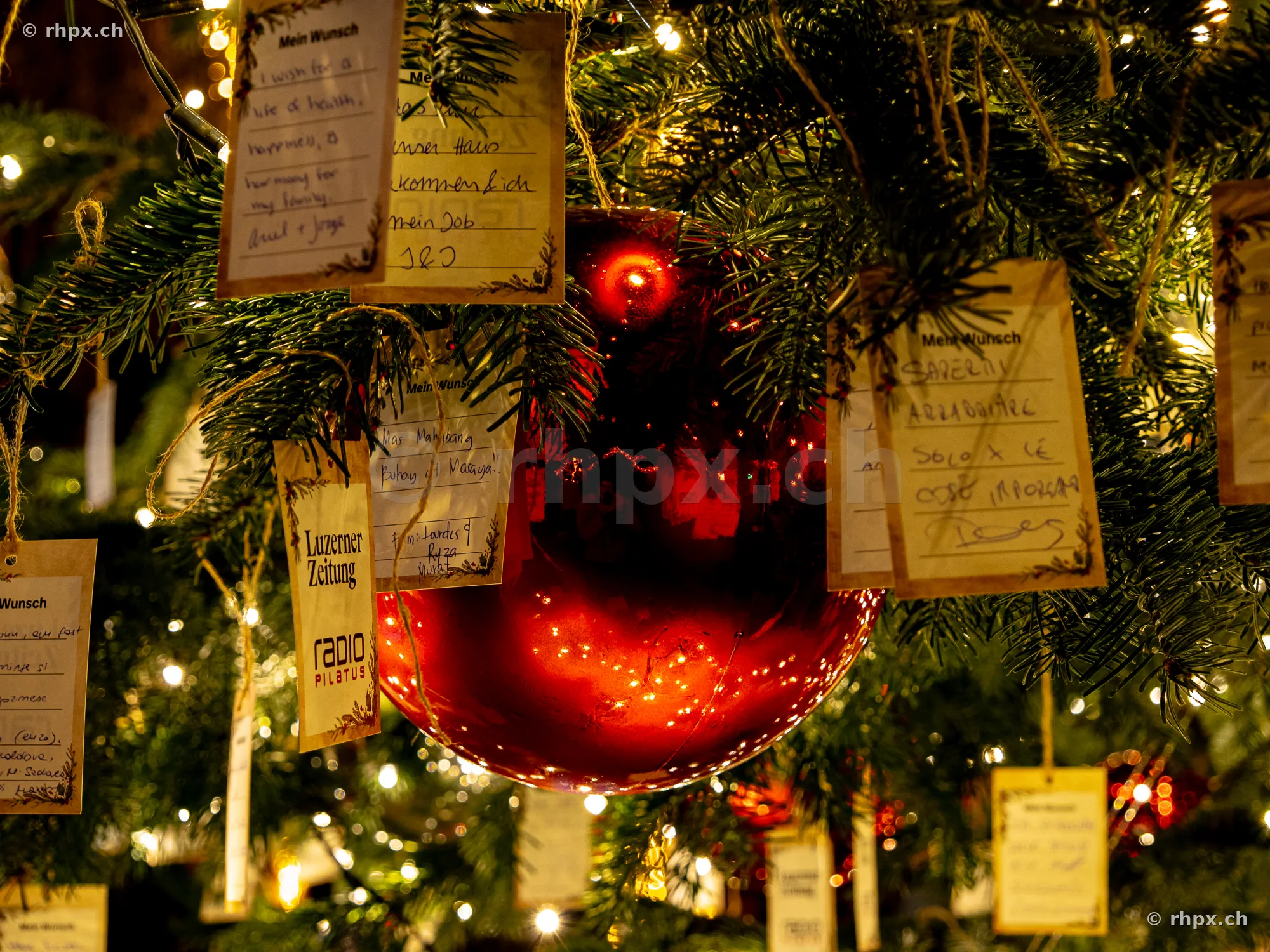 Red Christmas bauble on a tree with handwritten wish notes in Lucerne